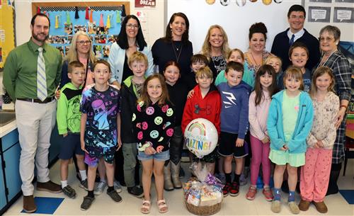 Image of Mrs. Witt, GCPS TOY, posed with administrators and students in a classroom.